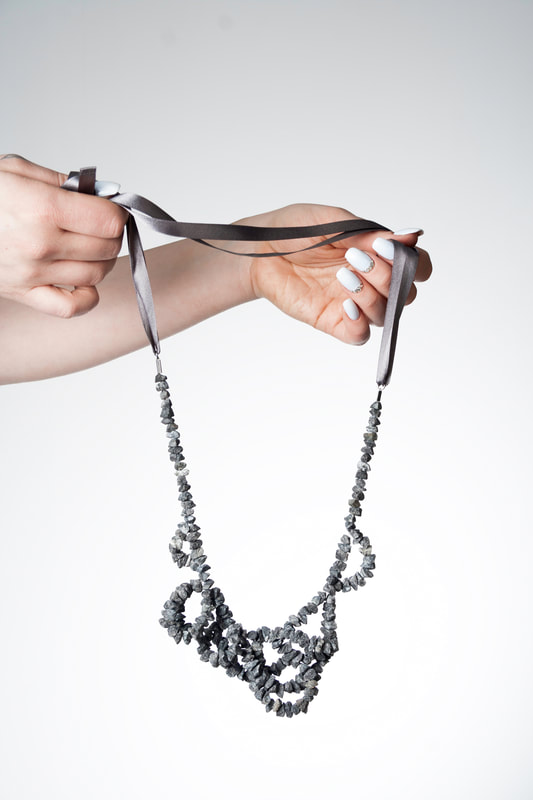 Hands holding a granite necklace by Hanna Ryynänen
