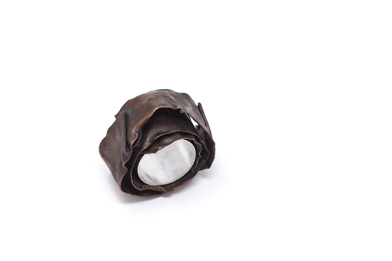 Chunky silver and copper ring in patinated brown color on white background