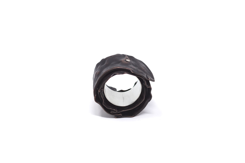 Chunky silver and copper ring in patinated dark brown color on white background