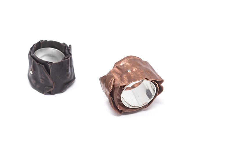 Two large silver and copper rings, one in dark brown patina color and other in natural copper on white background