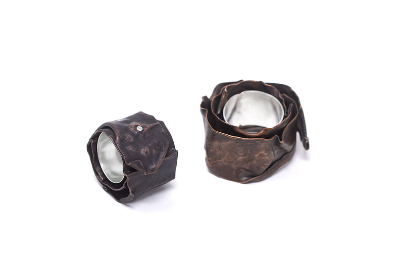 Two large silver and copper rings in dark brown patina color on white background
